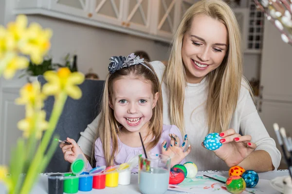 Mãe feliz e filha pintando ovos de Páscoa na sala de estar — Fotografia de Stock