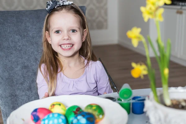 Smiling little girl coloring easter eggs — Stock Photo, Image