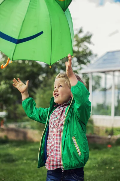 Adorable toddler boy play with green umbrella — Stok fotoğraf