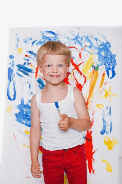 Pintura de criança com quadro de pincel no cavalete. Educação. Criatividade. Estúdio retrato sobre fundo branco — Fotografia de Stock