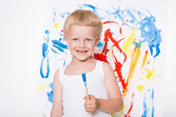 Artista niño preescolar pintura pincel acuarelas en un caballete. En la escuela. Educación. Creatividad. Estudio retrato sobre fondo blanco —  Fotos de Stock