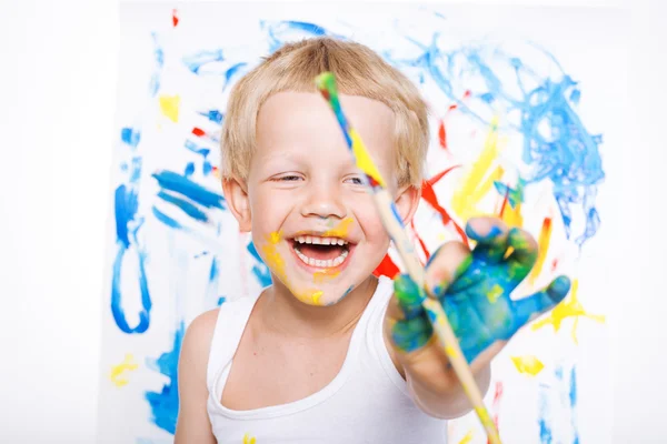 Pequena pintura criança bagunçada com pintura pincel no cavalete. Educação. Criatividade. Na escola. Pré-escolar. Estúdio retrato sobre fundo branco — Fotografia de Stock