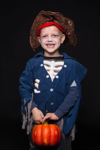 Kleiner Junge im Halloween-Kostüm eines Piraten, der mit Kürbis vor schwarzem Hintergrund posiert. Studioporträt — Stockfoto