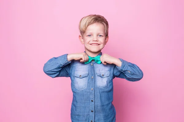 Junger gutaussehender Junge mit blauem Hemd und Schmetterlingskrawatte. Studioporträt über rosa Hintergrund — Stockfoto