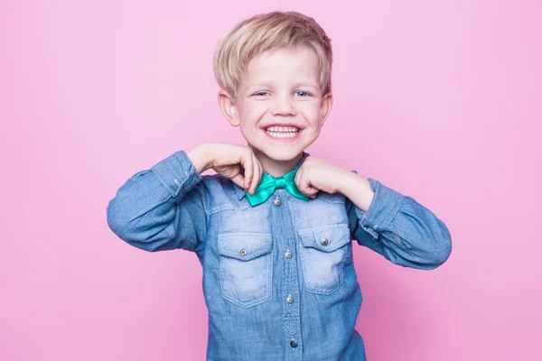青いシャツと蝶ネクタイで笑顔の若いハンサムな子供。ピンクの背景にスタジオの肖像 — ストック写真