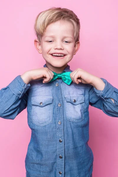年轻英俊的小伙子笑着，穿着蓝色的衬衫，打着蝴蝶领带。粉红背景的工作室肖像 — 图库照片