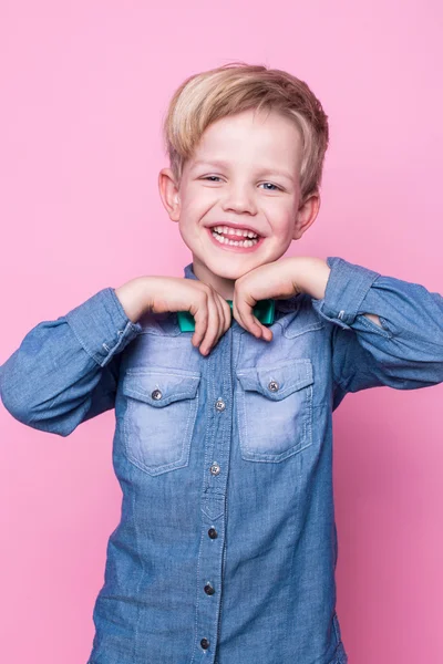Młody przystojny dzieciak uśmiechnięty niebieską koszulą i motylkowym krawatem. Studio portret na różowym tle — Zdjęcie stockowe