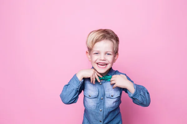 Young handsome kid smiling with blue shirt and butterfly tie. Studio portrait over pink background Stock Photo