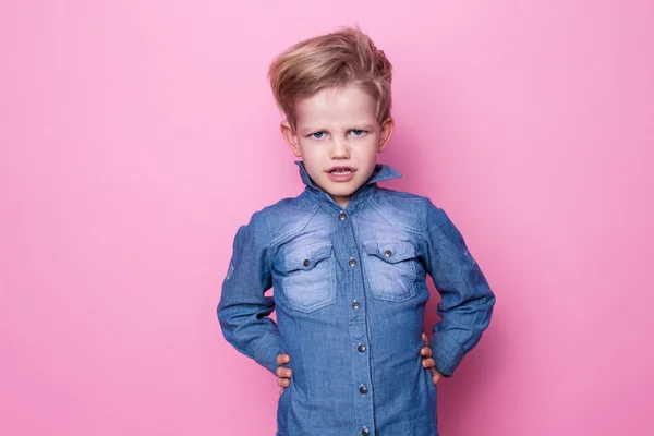 Retrato de um rapazinho lindo e zangado. Retrato de estúdio sobre fundo rosa — Fotografia de Stock