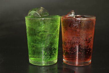 Kırmızı ve yeşil su ve buz bir cam siyah bir zemin üzerine.