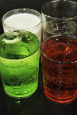 Kırmızı ve yeşil süt ve bir siyah arka plan üzerine bir bardak buz.