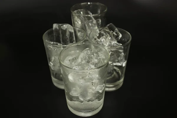 Is i ett glas på svart bakgrund. — Stockfoto