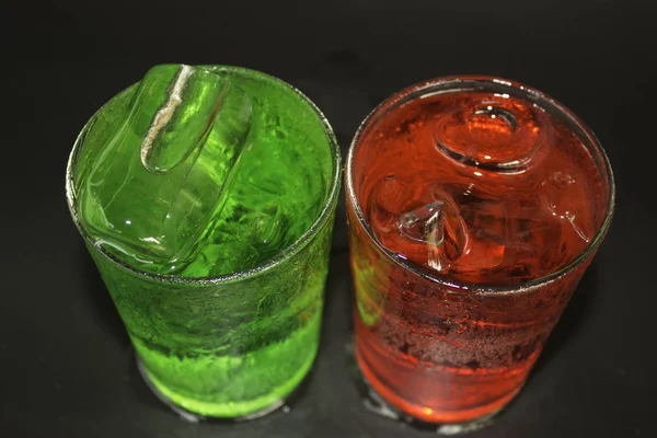 Agua roja y verde y hielo en un vaso sobre un fondo negro . —  Fotos de Stock