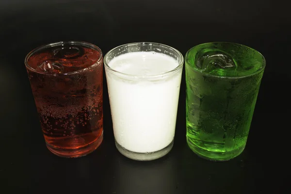 Röd och grön mjölk och isen i ett glas på svart bakgrund. — Stockfoto