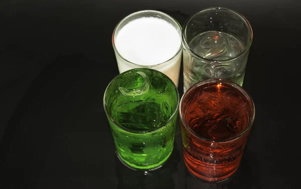 Röd och grön mjölk och isen i ett glas på svart bakgrund. — Stockfoto
