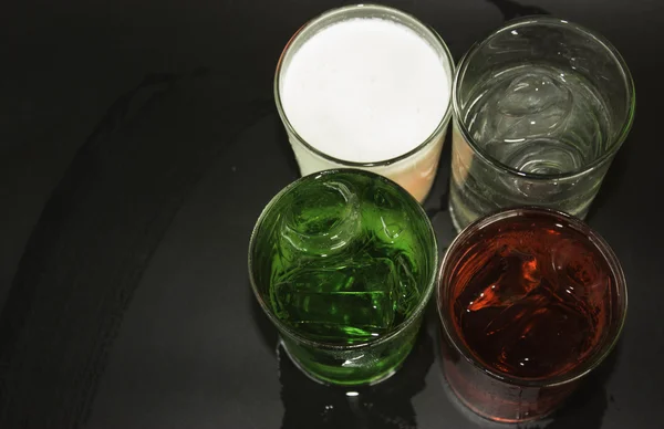 Červené a zelené mléko a ledu do sklenice na černém pozadí. — Stock fotografie