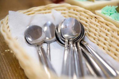 Kaşıklar hasır sepetin içinde temiz. Servis masasındaki çatal bıçak takımı..