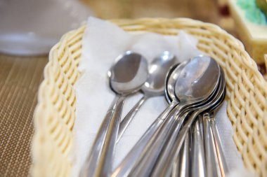 Kaşıklar hasır sepetin içinde temiz. Servis masasındaki çatal bıçak takımı..