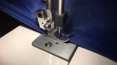 İşçi dikiş makinesine bez dikiyor. Kumaştaki ipliği ayırır.