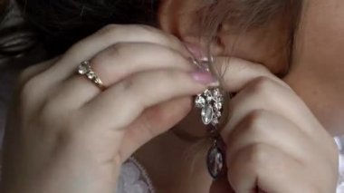 Kız onun kulağına takı küpesini ilikler. Bir parti için bijouterie giydirme.