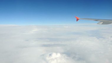 Büyük bulutların üzerinde kanat uçakları. Kabarık beyaz bulutlar gökyüzünden görünüyor.
