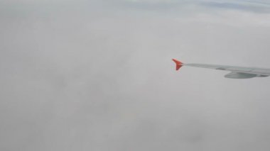 Büyük bulutların üzerinde kanat uçakları. Kabarık beyaz bulutlar gökyüzünden görünüyor.