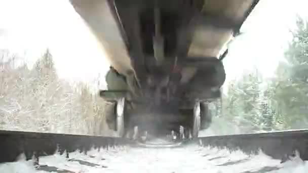 看到卡车在火车底部疾驰而过 雨在冬天的森林里移动 北方公路上装有油箱和气罐的多列火车 — 图库视频影像