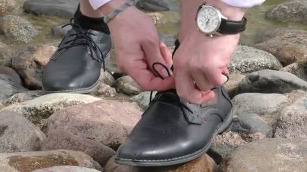 Ayakkabı bağları bağlayan adam, kıyıda dikilen.. — Stok video
