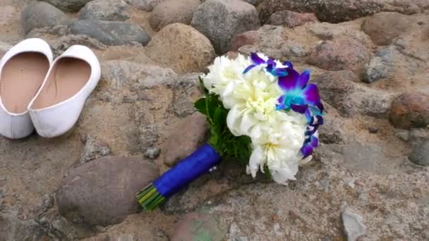 The brides bouquet and white shoes abandoned on the beach. — Stock Video