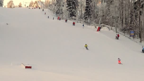 Lyžaři turisté šplhají na svah lyžařských vleků při západu slunce. — Stock video