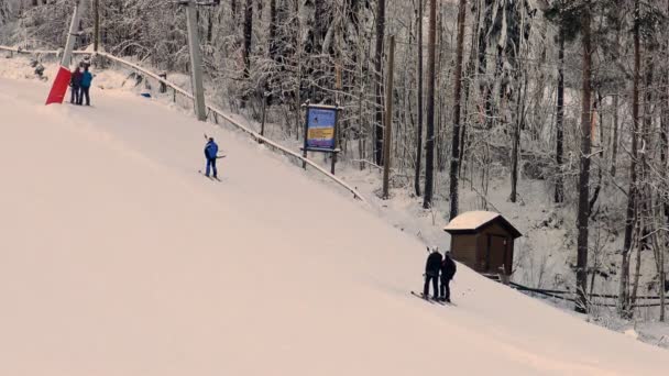 Síelők turisták mászni a lejtőn a sífelvonók naplementekor. — Stock videók