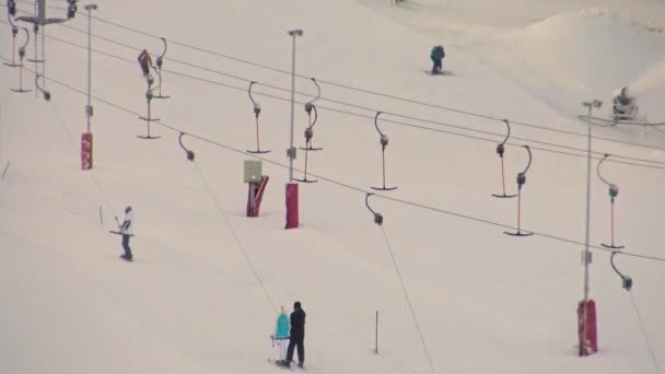 スキー観光客は日没時にスキーリフトの斜面に登る 冬のスポーツとアクティブなレジャー リゾートの雪の丘でスキー — ストック動画