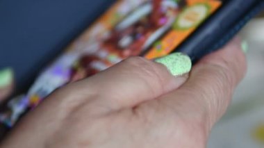 Yaşlı bir kadın telefon ekranından sosyal ağlara bakıyor. Yaşlılar iletişim için yeni mobil teknolojiler öğreniyor.