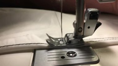 İşçi dikiş makinesine bez dikiyor. Kumaştaki ipliği ayırır.