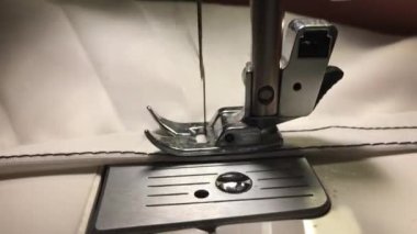 İşçi dikiş makinesine bez dikiyor. Kumaştaki ipliği ayırır.