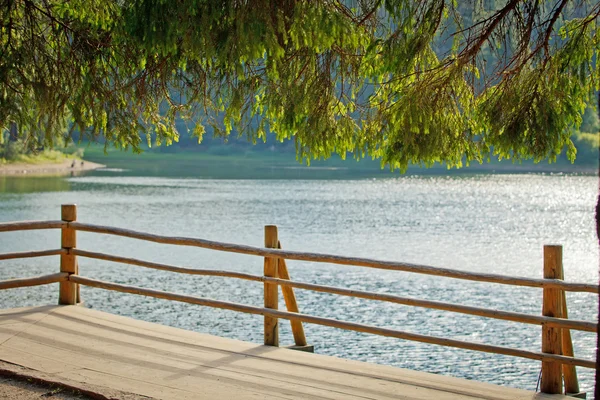 Corrimão de madeira romântico contra o lago azul — Fotografia de Stock