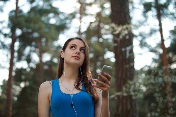 10 代の若い女性が公園で彼女のスマート フォンで音楽を聴く — ストック写真