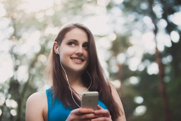 Jonge tiener vrouw naar muziek luisteren op haar smartphone in park — Stockfoto