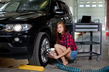 Female mechanic changing tire with air impact wrench