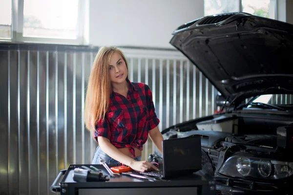 Kobiece mechanik w kraciastej koszuli, w pracy. Auto service station. — Zdjęcie stockowe