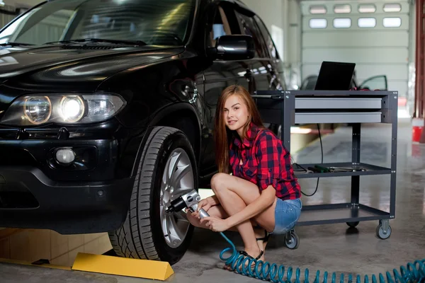 Female mechanic changing tire with air impact wrench — Stock Photo, Image