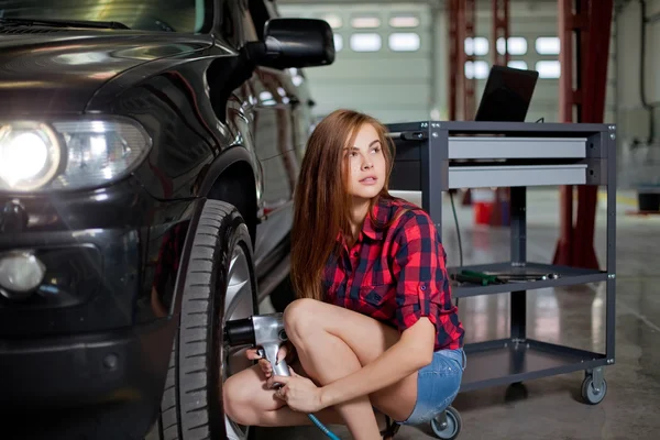 Female mechanic changing tire with air impact wrench