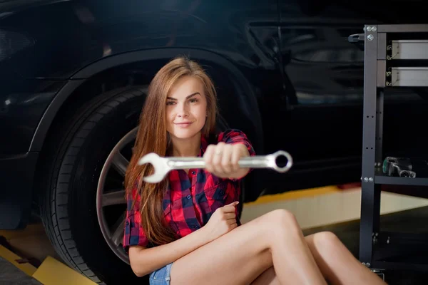 一个年轻的女人，作为一个在车库里用扳手的技工 — 图库照片