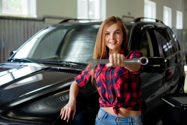 Une jeune femme mécanicienne dans un garage avec clé Image En Vente