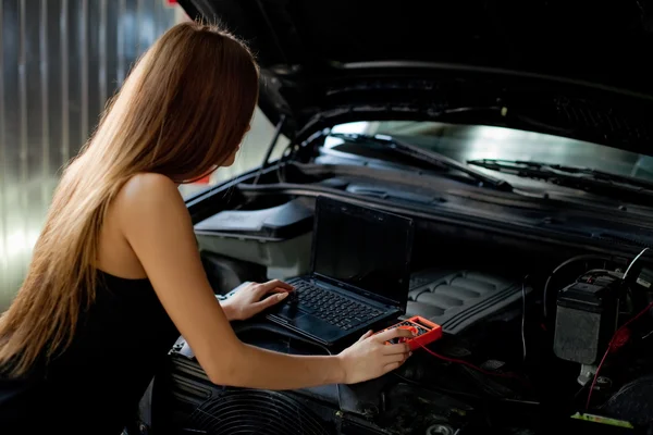 Młoda seksowna brunetka mechanik w kraciastej koszuli, w garażu. Auto di — Zdjęcie stockowe