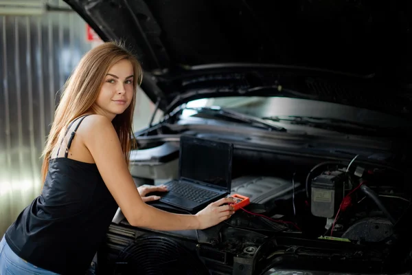 Młoda seksowna brunetka mechanik w kraciastej koszuli, w garażu. Auto di — Zdjęcie stockowe