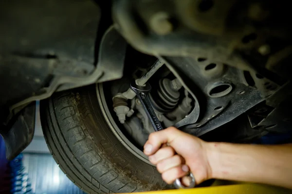 Element of Auto mechanic working underneath a lifted car — Stock Photo, Image