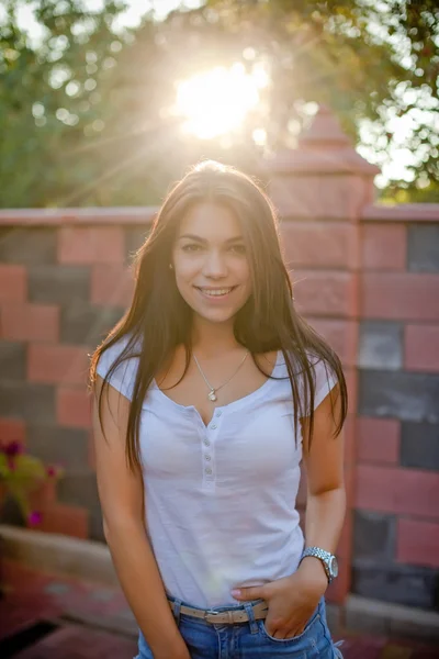 Smiling young brunette woman posing in yard of her residence — Stock Photo, Image