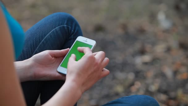 Ένα κορίτσι που χρησιμοποιεί το τηλέφωνο με πράσινη οθόνη στη φύση. Γκρο πλαν — Αρχείο Βίντεο