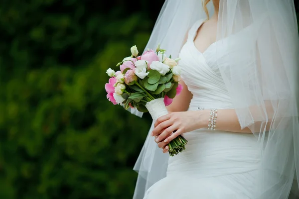 Gros plan du bouquet de mariage de roses dans les mains d'une mariée mince en — Photo